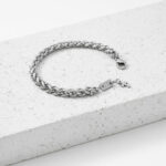 Pulseira para homem em aço entrelaçado com pendente em forma de cruz.